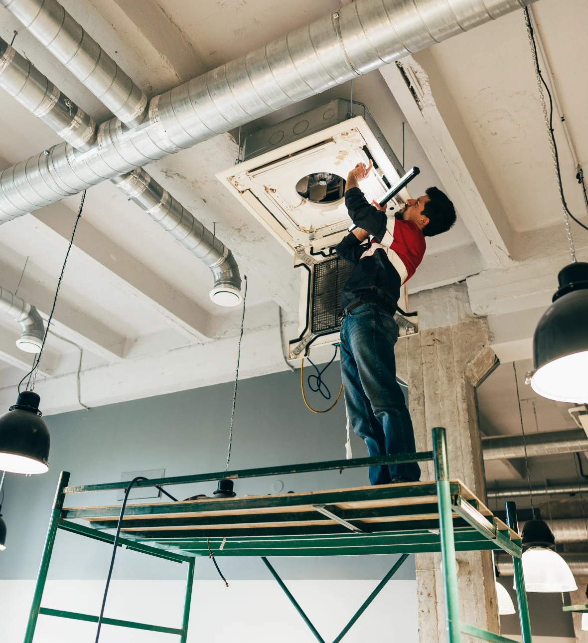 Worker on scaffold fixing HVAC system