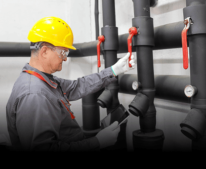 Worker inspecting industrial pipes